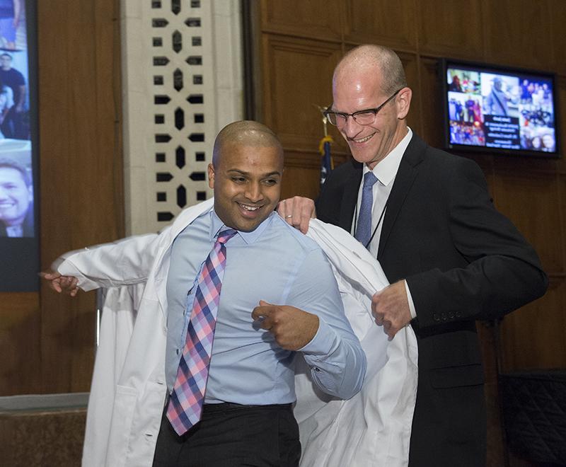 A graduate student receives his white coat.